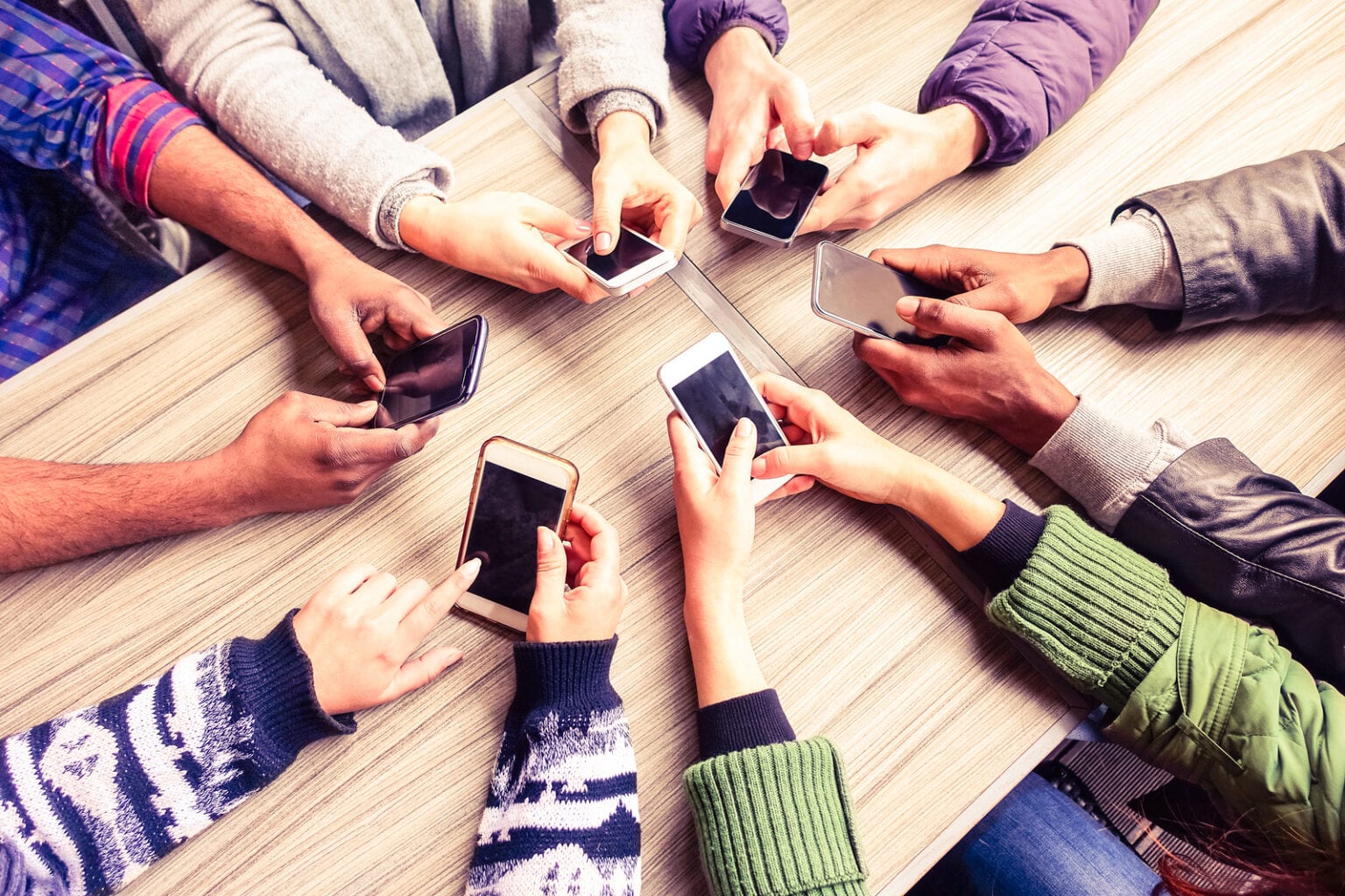 group-of-friends-hands-with-cell-phones-in-circle